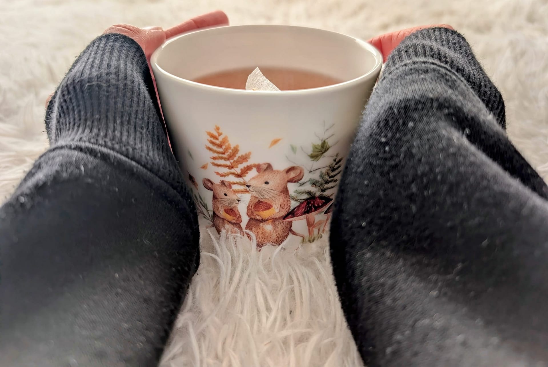 A person holding a warm cup of tea wrapped in cosy clothing, representing rest and reflection on autistic masking