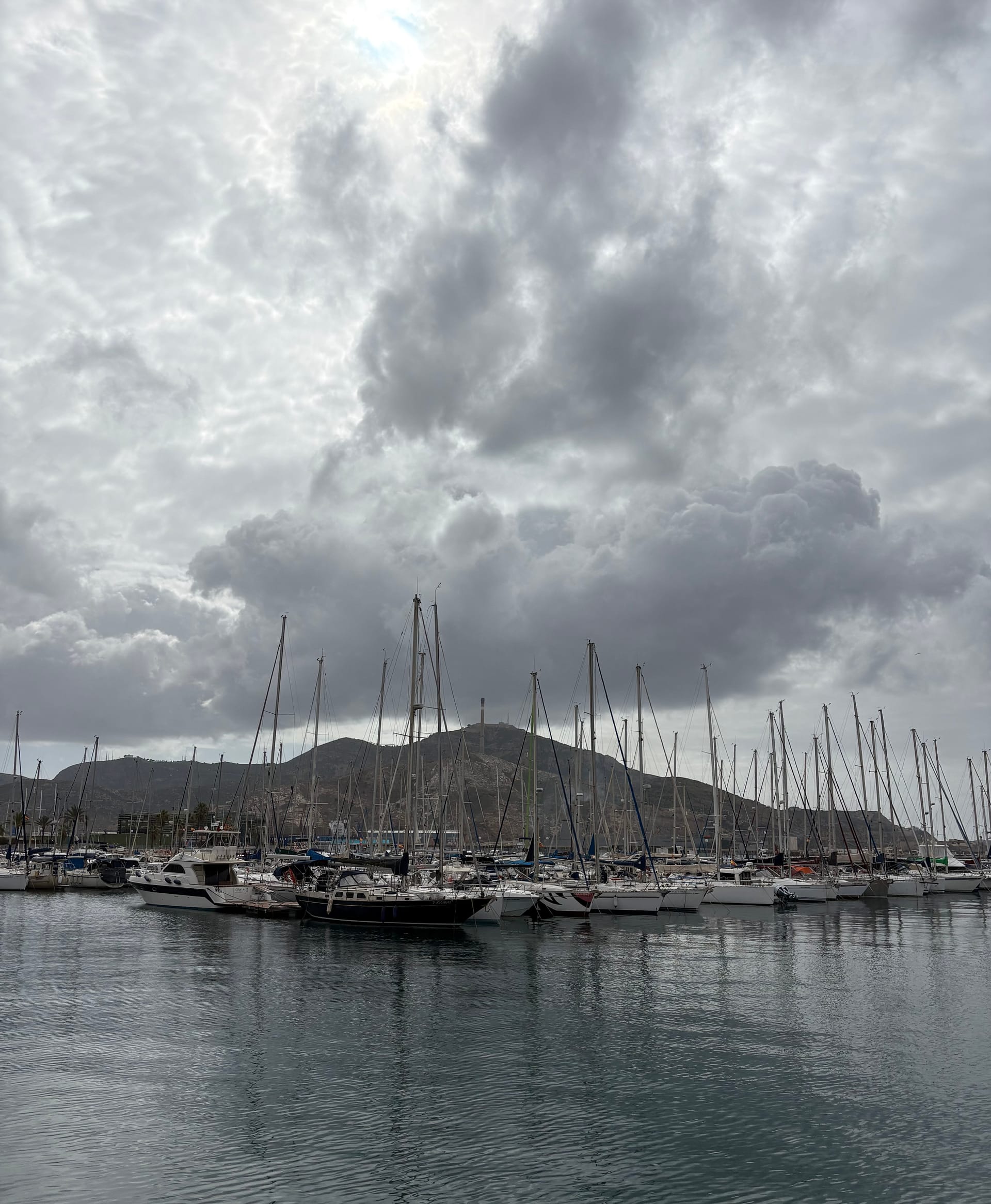 Clouds building over a marina in southern Spain, reflecting the feeling of autistic overwhelm on holiday